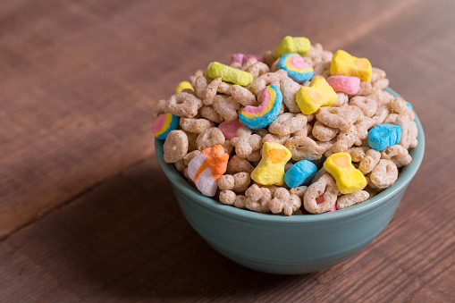 Colorful marshmallow cereal in a blue bowl on a weathered wood background