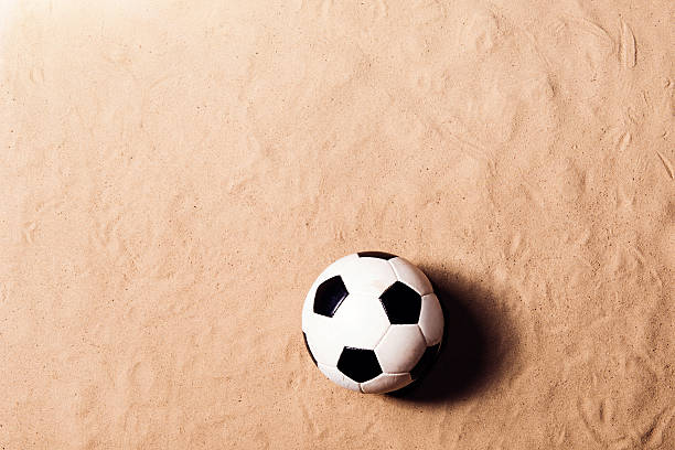 pelota de fútbol contra playa de arena. toma de estudio. espacio de copia. - beach football fotografías e imágenes de stock