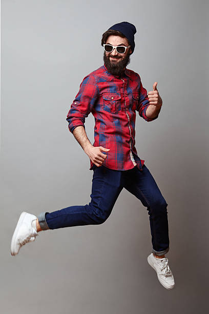Happy man in air with thumbs up Happy hipster young man with beard in air with thumbs up on grey background air jump stock pictures, royalty-free photos & images