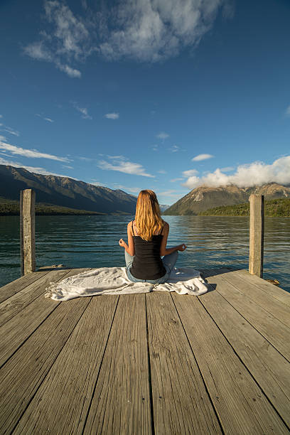 jovem mulher relaxa no lago pier, exercícios de ioga - lake tranquil scene landscape zen like - fotografias e filmes do acervo
