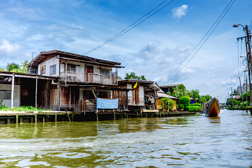 Bangkok, Thailand - July 25, 2014: Wooden houses on stilts on the riverside of Chao Praya River. The Chao Phraya is a major river in Thailand, with its low alluvial plain forming the centre of the country. It flows through Bangkok and then into the Gulf of Thailand.