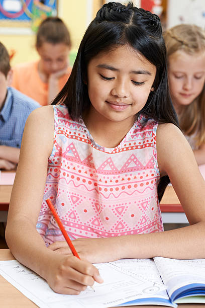 istock Female Elementary School Pupil Working At Desk 547154924
