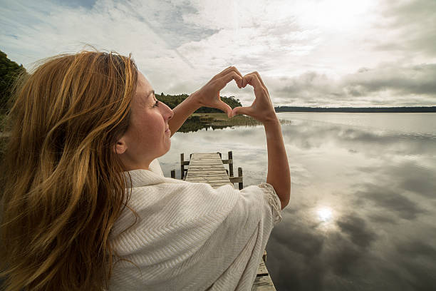 istock Woman frames mountain lake landscape into heart shape 547156074