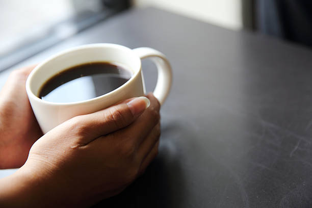 istock Black coffee with hand on wood background in coffee shop 547158438
