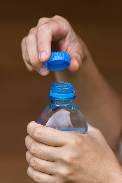hands opening bottle with fresh water, closeup hands holding bottle with fresh clean water on blurred background opening bottle cap photos stock pictures, royalty-free photos & images