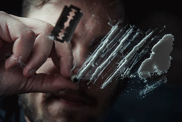 Cocaine Man snorting cocaine in dark room. Drug addict concept. snorting stock pictures, royalty-free photos & images