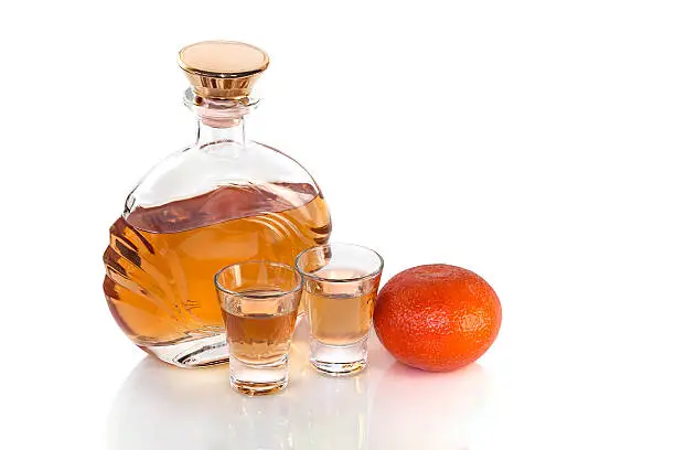 Bottle with glasses of tequila and tangerine on white background