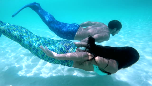 mermaid couple swimming underwater from tropical beach