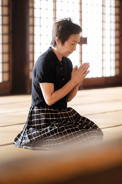 istock Senior Woman Praying in Buddhist Temple 547199874