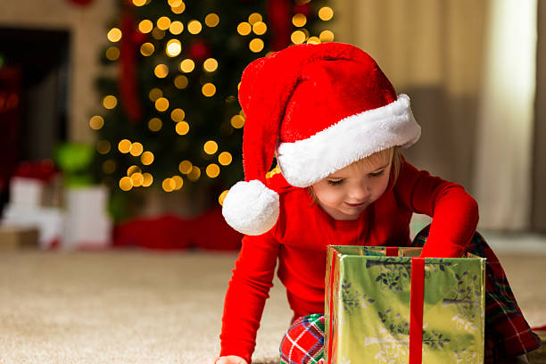 istock Cute Christmas toddler opening up a gift 547201300