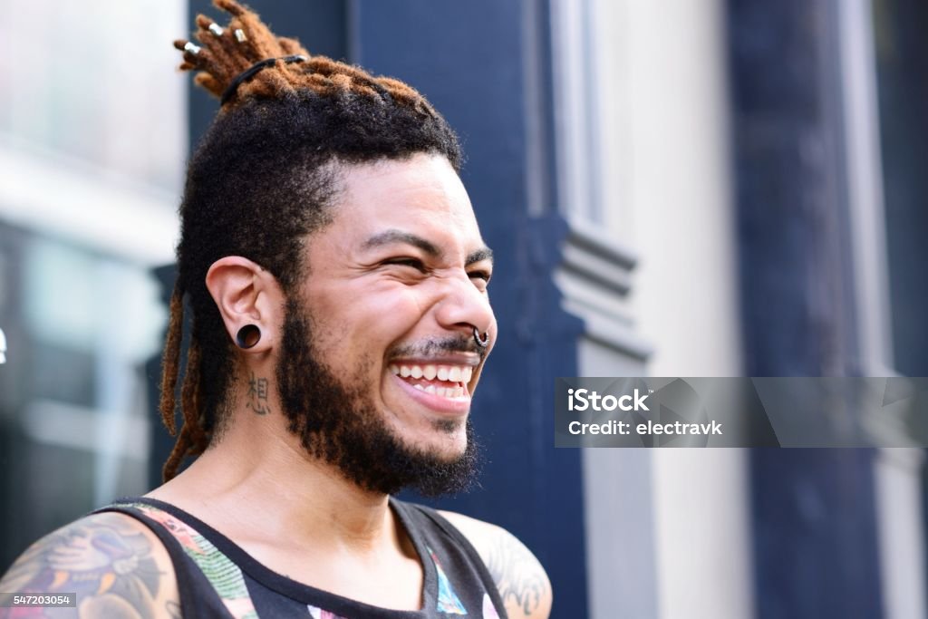 Young man laughing A fashionable young man looking away from the camera, laughing. Tattoo Stock Photo