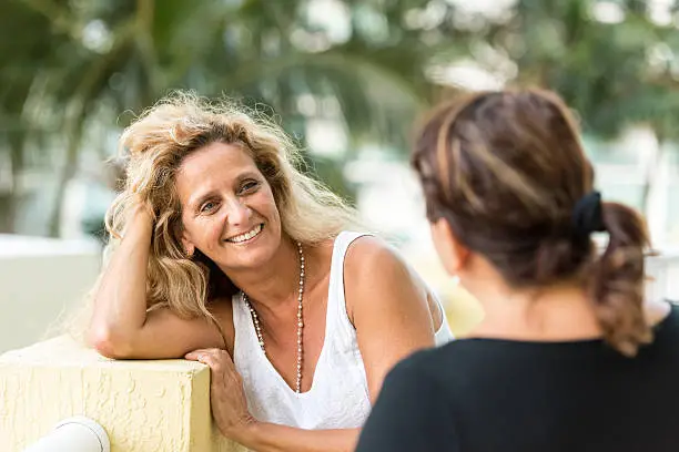 Two Caucasian mature women talking smiling