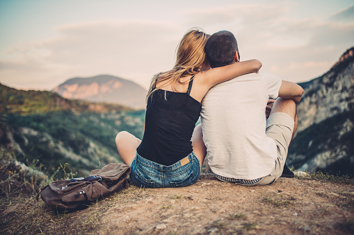 Couple in love hugging and sitting on the top of mountains and woods in summer.