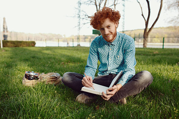 istock Young happy ginger man relaxing on the grass 547211020