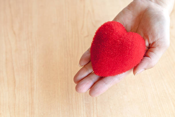 istock Red heart in hand wooden background 547211332