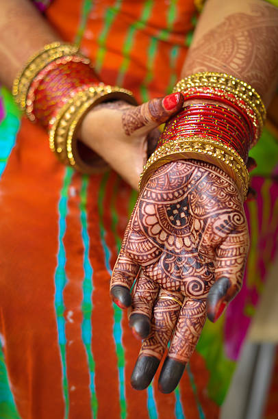 istock Indian woman's hand with henna tattoo and red bangles 547211644