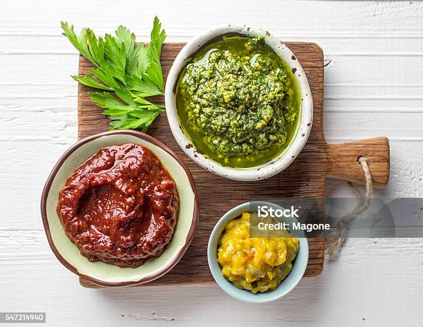 Various Sauces On Wooden Cutting Board Stock Photo - Download Image Now - Pesto Sauce, Barbeque Sauce, Condiment