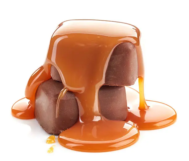 Photo of caramel sauce pouring on chocolate candies