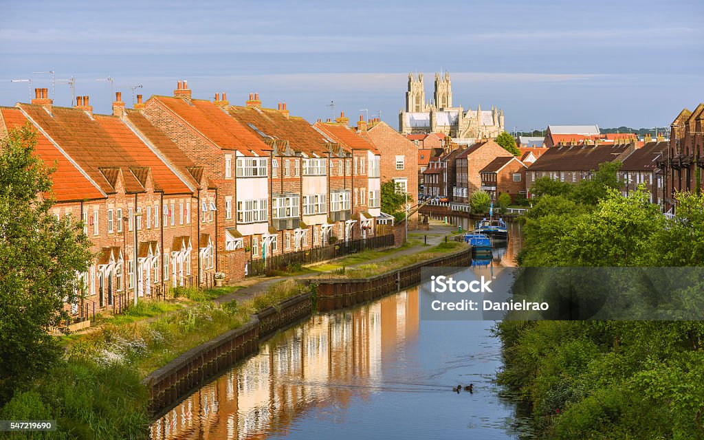 The minster, town houses, and the beck, Beverley, Yorkshire, UK. Beverley, Yorkshire, UK. The ancient minster, town houses, and the beck (canal) with barges at sunrise on a peaceful summer morning in Beverley, Yorkshire, UK. Beverley - Yorkshire Stock Photo