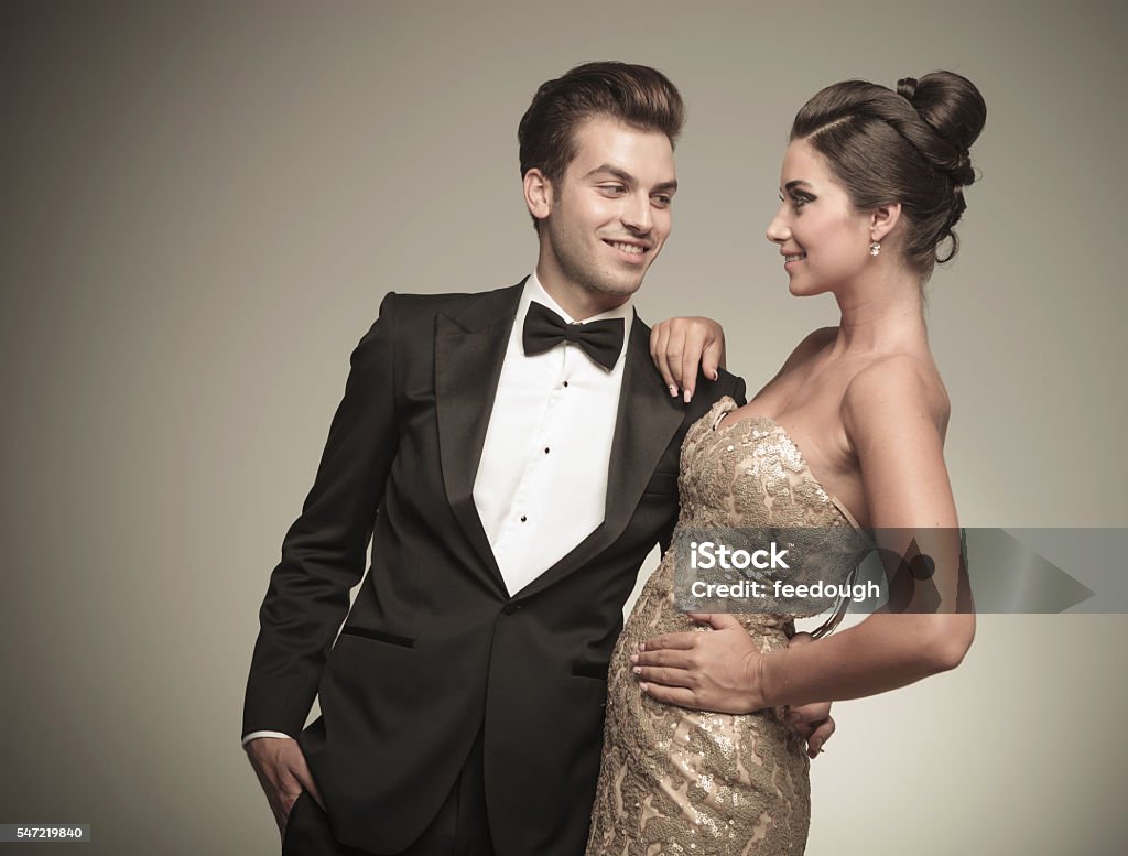 handsome man looking at his wife while embracing her. Smiling young handsome man looking at his wife while embracing her. Formalwear Stock Photo