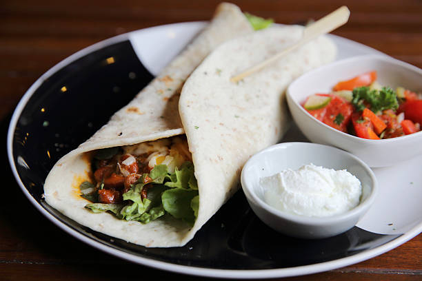 istock Mexican burritos on a plate with tomato salad 547221042