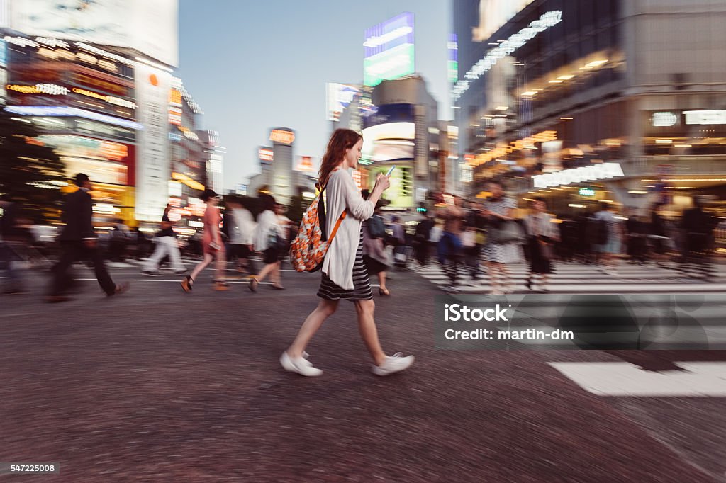 Woman texting at Shibuya crossing Smiling woman walking and texting on smartphone.Photo from Istockalypse 2016 Walking Stock Photo