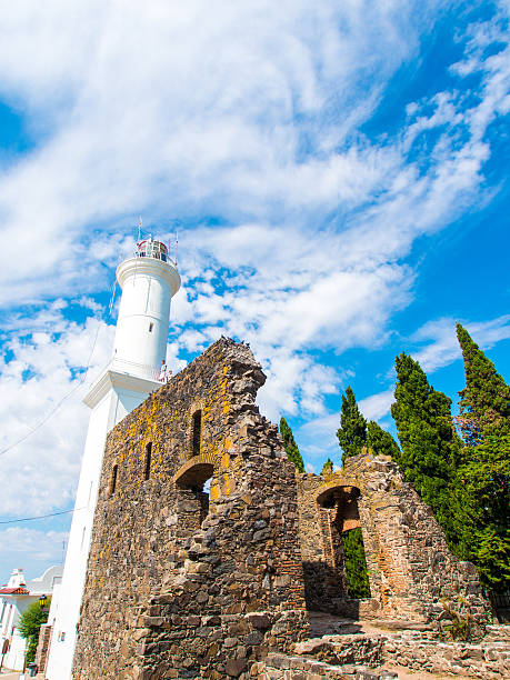 Colonia del Sacramento - January 24, 2013: A lighthouse stands beside a run-down building in Colonia del Sacramento, Uruguay. People can be seen exploring the lighthouse upon closer inspection.