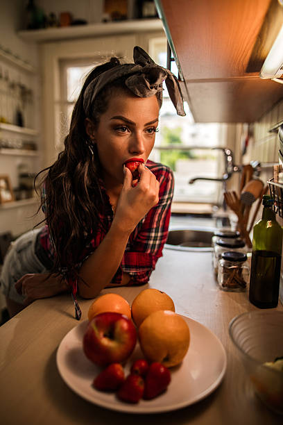 istock Seductive retro styled woman eating strawberry in the kitchen. 547230308