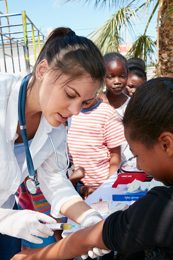 Shot of a volunteer nurse giving injections to underprivileged kids