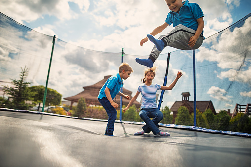 Little boys aged 6 and the girl aged 10 having fun on trampoline. 