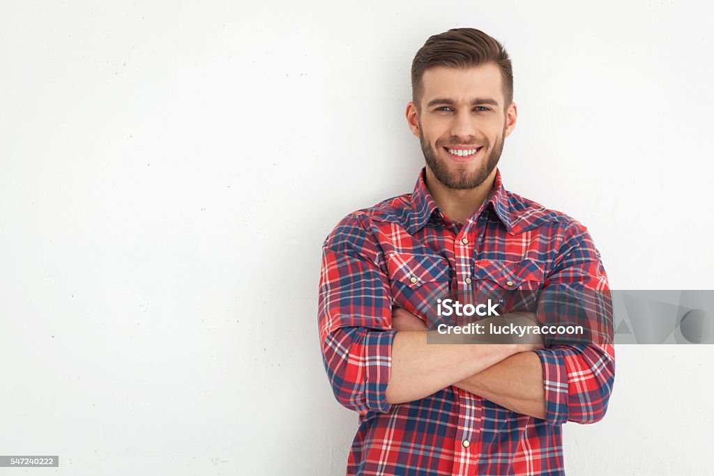 Handsome young guy standing against white wall. Portrait of handsome young guy standing against white wall. Men Stock Photo