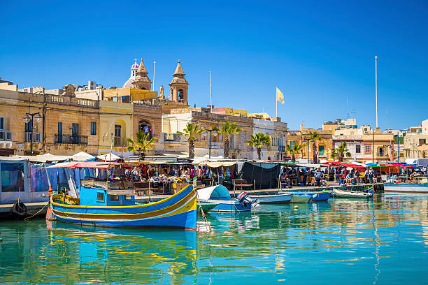 Marsaxlokk market with traditional Luzzu fishing boats Malta - Marsaxlokk market with traditional Luzzu fishing boats on a beautiful summer day withblue sky and green sea malta stock pictures, royalty-free photos & images