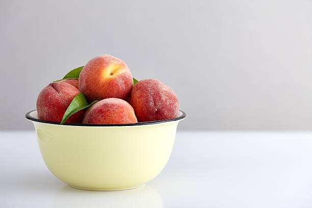 istock Ripe peaches in bowl isolated on white 547245826