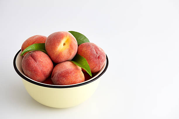 Ripe peaches in bowl isolated on white