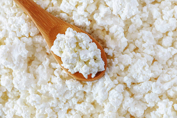 crumbly cottage cheese in the wooden spoon stock photo