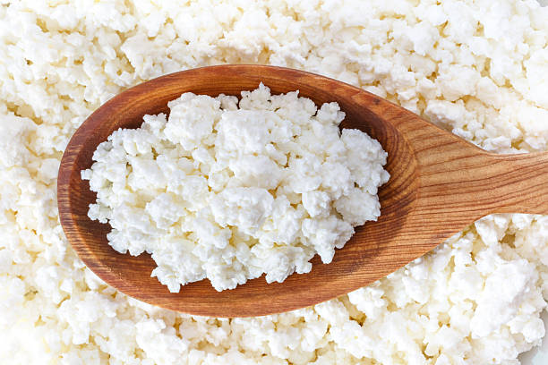 crumbly cottage cheese in the wooden spoon stock photo