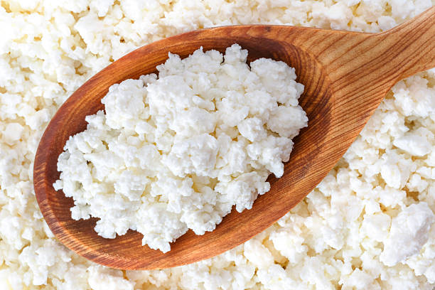 crumbly cottage cheese in the wooden spoon stock photo