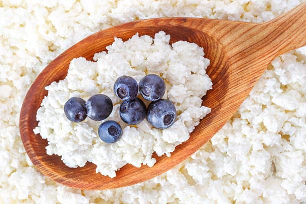 crumbly cottage cheese in the wooden spoon with blueberries stock photo