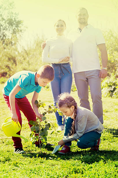 istock Parents with two kids planting a bush 547410338