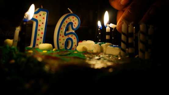 Lighting the candles on a birthday cake for a sweet 16 birthday.