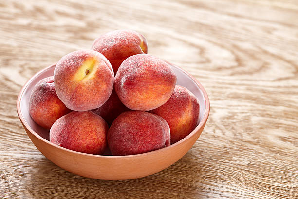 melocotones maduros en cuenco sobre fondo de madera - peach nectarine portion fruit fotografías e imágenes de stock