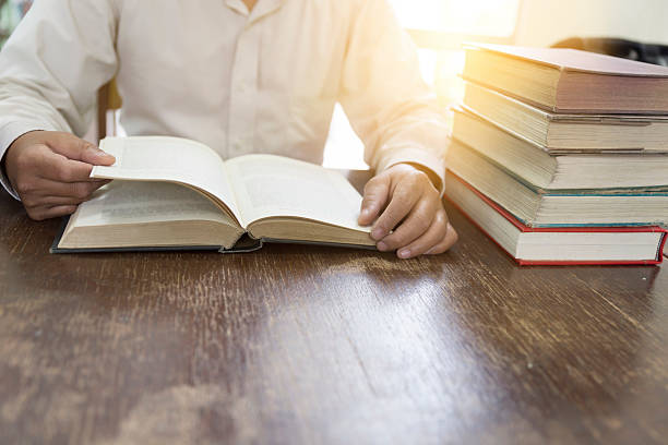 istock man reading book with textbook stack on wooden desk 547414888