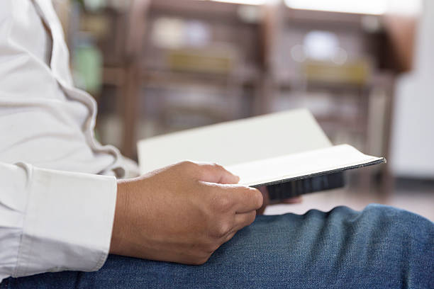 istock man reading book in aisle in library 547415076