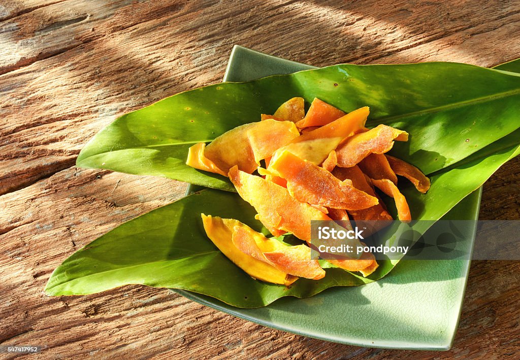 Snacks,preserved mango from Cebu,Philippines. Slices of preserved mango,sweet and sour dessert from Cebu,Philippines.Served on green leaves and placed on rustic wood background. Mango Fruit Stock Photo