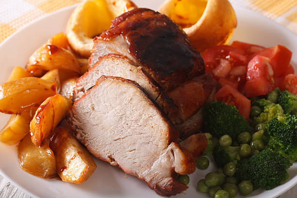 Sunday roast: pork with vegetables and Yorkshire pudding Sunday roast of baked pork with vegetables and Yorkshire pudding close-up, horizontal carving set stock pictures, royalty-free photos & images