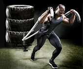 Muscular athlete pulling sled of tires.