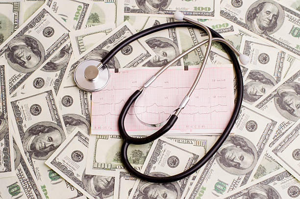 istock stethoscope over ecg graph and 100 dollar bills 547424356
