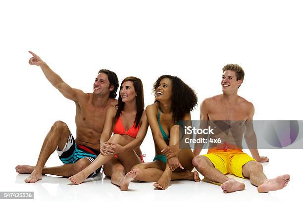 Lächelnd Vier Schwimmer Sitzend Und Zeigend Stockfoto und mehr Bilder von Weißer Hintergrund - Weißer Hintergrund, Bikini, Boden