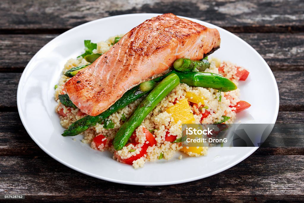 Pan fried salmon with tender asparagus and courgette served on Pan fried salmon with tender asparagus and courgette served on couscous mixed with sweet tomato, yellow pepper salsa Asparagus Stock Photo
