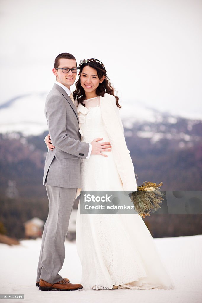 Asian Woman and Caucasian Man Wedding in Snow Mountains A young and attractive Asian woman and caucasian man get married in the mountains with snow from the previous winter still present. Adult Stock Photo